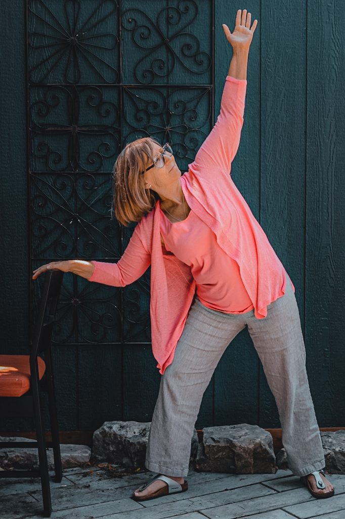 Heather Skoll performing warrior pose with chair support
